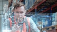 Warehouse worker using a large transparent computer touchscreen.