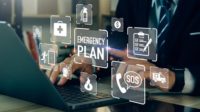 Businessman working on Emergency Plan on his laptop while icons float above the keyboard.