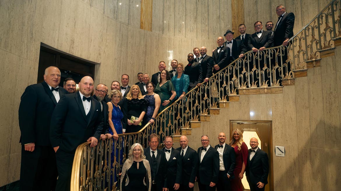 P-M & Associates Team posing for a group photo on the stairs at its 50th anniversary celebration gala.