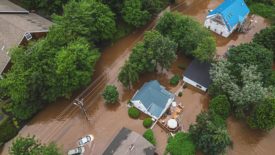 Overview of houses and cars in a severely flooded area.